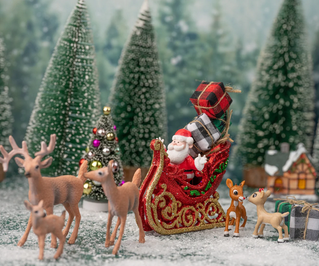 Un père Noël sur un traîneau tiré par des rennes dans une forêt enneigée entouré de sapin et de cadeaux